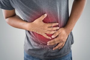 A men holding her stomach in discomfort, experiencing stress diarrhea.