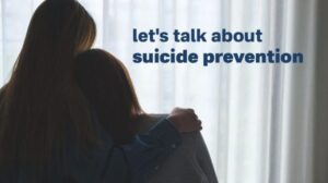 Two people embracing with text 'let's talk about suicide prevention' in the background.