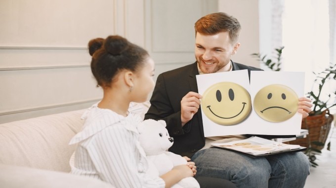 Therapist showing happy and sad emotion cards to a child during a counseling session.
